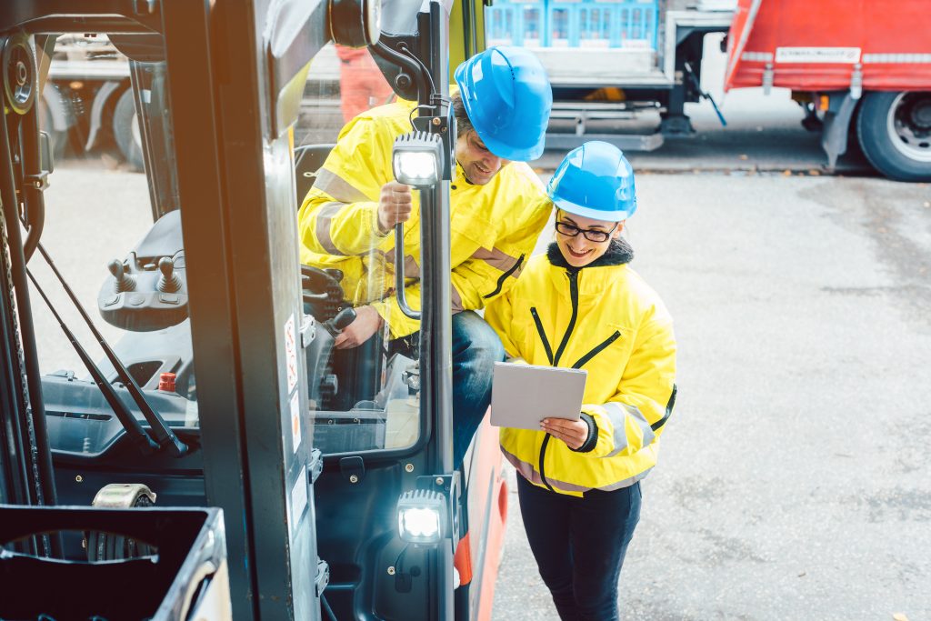 Worker and manager at distribution center behind a forklift